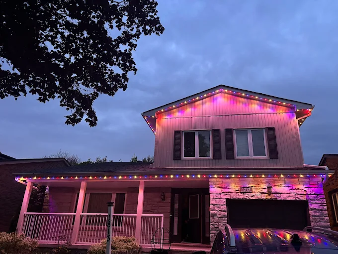 Multicolour festive lighting along the roofline at dusk