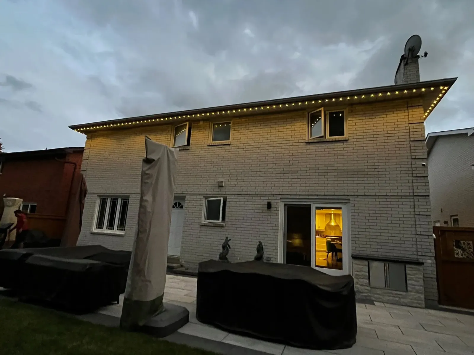 Roofline lighting along the back of a brick home at dusk