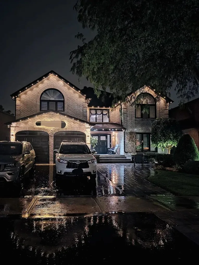 Soft roofline lighting on a brick home on a rainy night