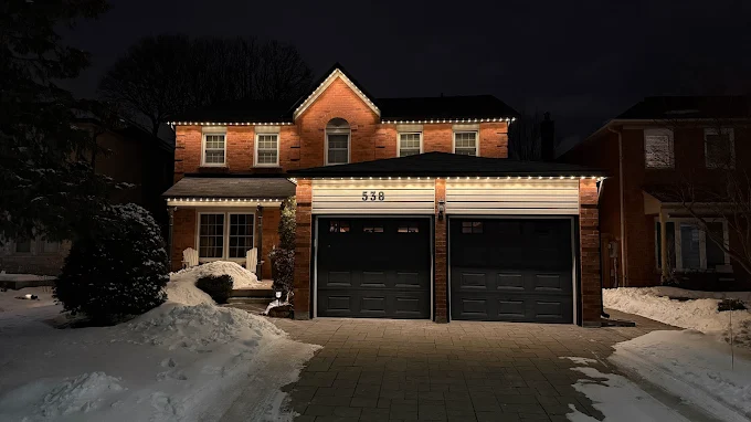 Warm white roofline lighting on a home after a snowfall